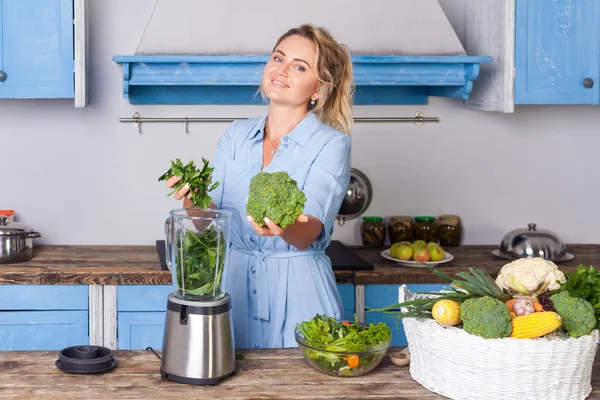 Glada kvinna som håller gröna grönsaker och sätta ingredienser — Stockfoto