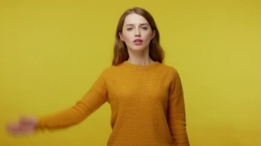 Yes sir! Serious young woman with cute appearance and in pullover giving salute with confident responsible expression, obedient performer ready to do order. studio shot isolated on yellow background