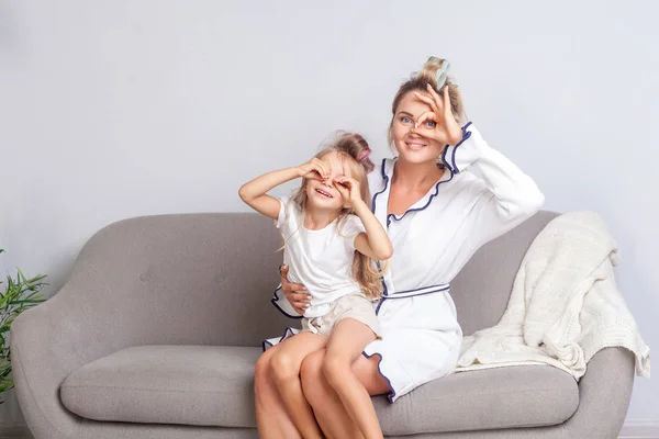 Alegre feliz mamá y su hija con rulos en el pelo mirando ca — Foto de Stock