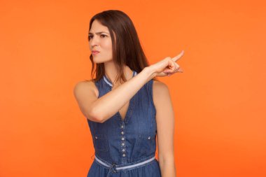 Çık dışarı! Sinirli, kot elbiseli esmer kadın işaret ediyor. 