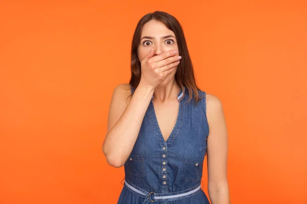 Τρομαγμένη μελαχρινή γυναίκα με denim φόρεμα που καλύπτει το στόμα με ένα χέρι — Φωτογραφία Αρχείου