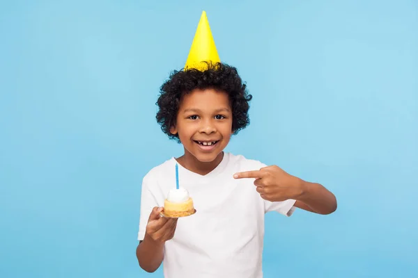 Lille bedårende, lykkelige gutt med en festlig kjegle på hodet som peker – stockfoto