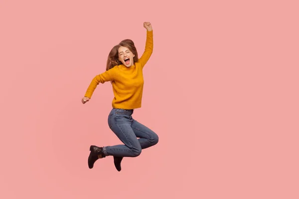 Lebhaftes, energiegeladenes Ingwermädchen in Pullover und Jeans springt in die Luft — Stockfoto
