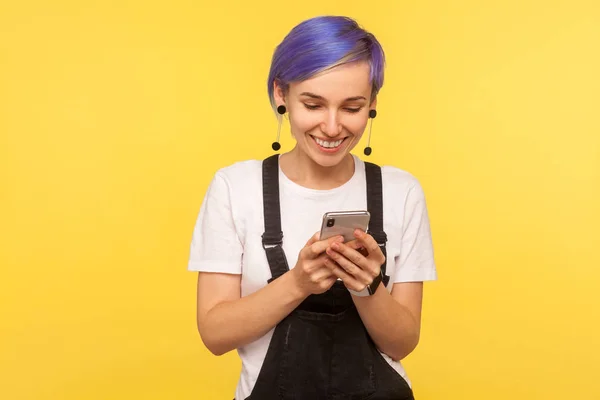 Portrait of glad hipster girl using cell phone, texting or readi — Stock Photo, Image