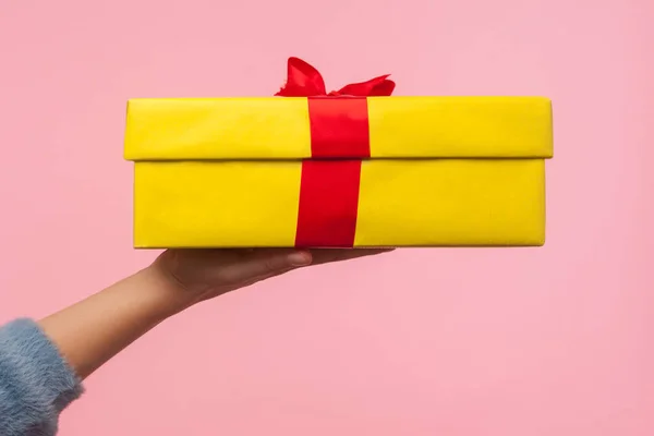 Nahaufnahme des Armes in warmem Pullover mit eingewickelter gelber Geschenkbox — Stockfoto