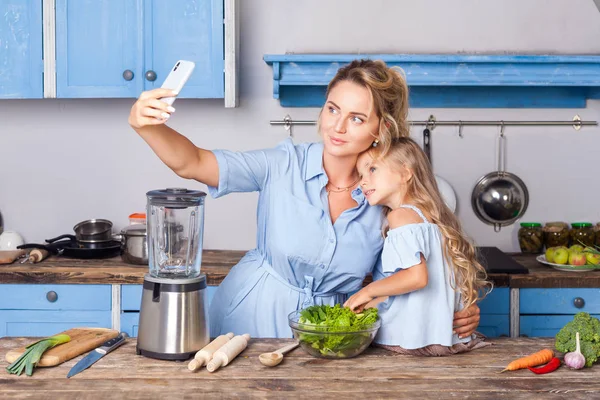 Charming woman and little girl taking selfie in modern kitchen, — Stock Photo, Image