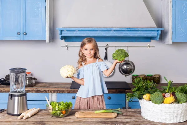 Cute little girl holding broccoli and cauliflower and smiling lo — 스톡 사진