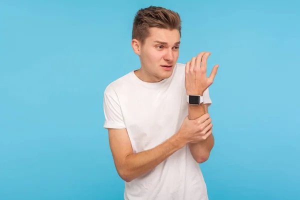 Injured hand. Man in white t-shirt holding arm and grimacing fro — 스톡 사진