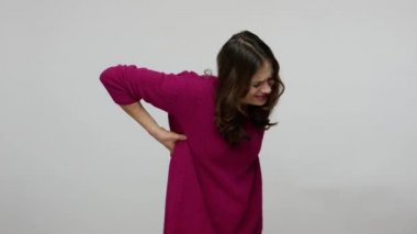 Young brunette woman grimacing from pain and doing self-massage, suffering lower backache