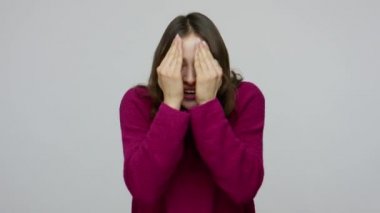 Peek a boo. Cheerful happy brunette girl in pullover playing hide and seek game, covering and opening her face with hands
