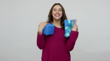 Fascinating excited brunette woman in pullover catching presents, holding gift boxes with expression of much joy