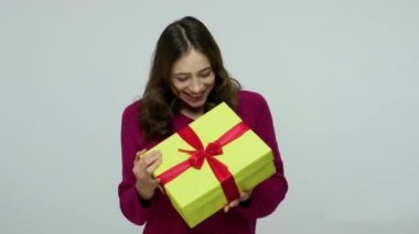 Charming beautiful happy brunette woman in pullover peeking inside gift box, curious about birthday present