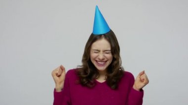 Happy positive excited brunette woman having fun, rejoicing at birthday party, dancing with funny cone
