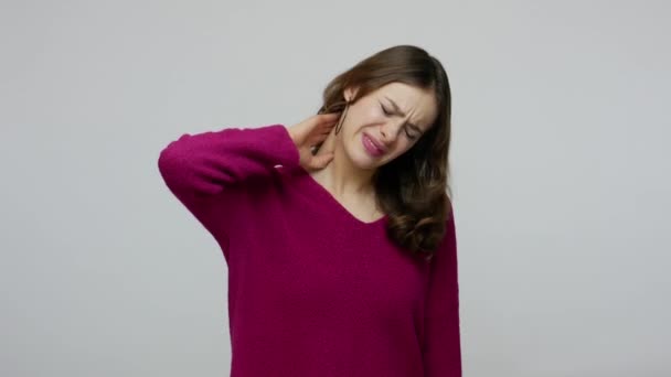 Нездоровая брюнетка женщина страдает сильной болью в шее делая массаж, имея мышечное напряжение или повреждение плеча — стоковое видео