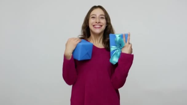 Fascinating excited brunette woman in pullover catching presents, holding gift boxes with expression of much joy — 图库视频影像