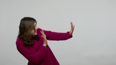 Phobia. Side view of frightened brunette woman in pullover shaking from fear and holding hands in defensive gesture