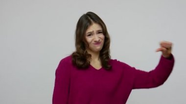 Dislike, bad service! Grumpy dissatisfied brunette woman in pullover showing thumbs down gesture