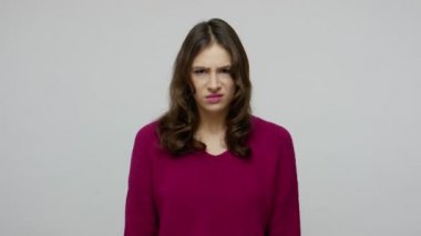 Don't want to watch! Brunette woman in pullover grimacing in disgust and covering eyes with hand