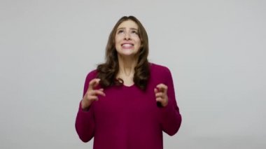 Cheerful brunette woman in anticipation of fortune looking imploringly, holding crossed fingers for good luck