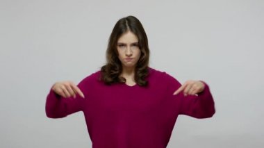 Here and right now. Angry bossy brunette woman pointing fingers down, demanding to come immediately