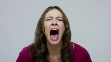 Mad scream. Closeup of furious brunette woman shouting loudly, yelling aggressively with crazy face