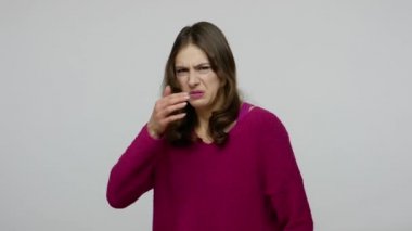 Unpleasant odor. Brunette woman grimacing in displeasure and pinching nose, gesturing go away