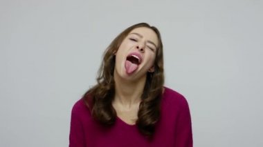 Naughty childish brunette woman in pullover showing tongue to camera and making fish face