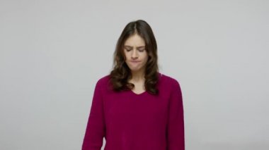 Depressed brunette woman looking at finger pistol with desperate helpless expression, performing suicide gesture