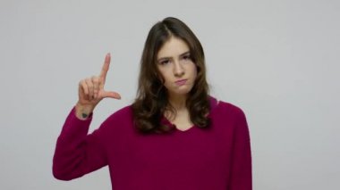 Angry brunette woman showing L sign with fingers, gesturing You are loser and pointing to camera