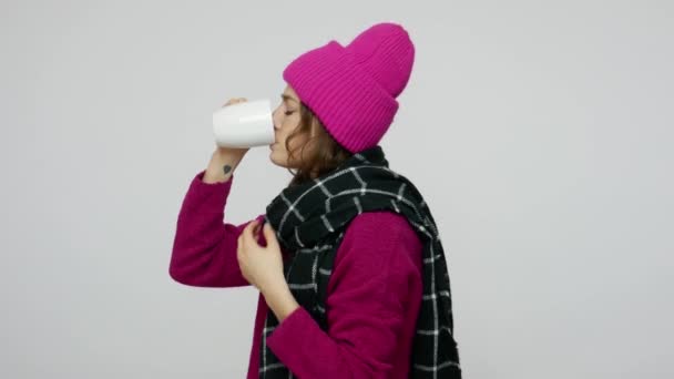 Side view of unhealthy brunette woman in winter hat and scarf suffering sore throat, drinking hot tea — 비디오