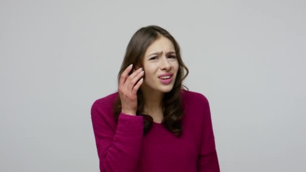Hearing problems, deafness. Nice-looking brunette woman in pullover holding hand near ear and asking what — Stok video