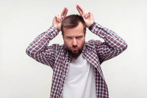 Portrait of angry bearded man showing bull horn gesture with puf — Stock Photo, Image