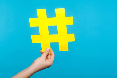 Kadın eli, büyük sarı hashtag işaretini tutuyor.