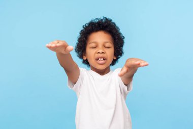Portrait of blind little curly boy walking with closed eyes and 