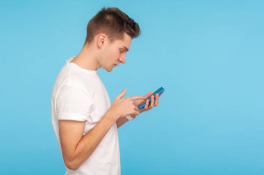 Side view of young man in white t-shirt using cellphone with foc