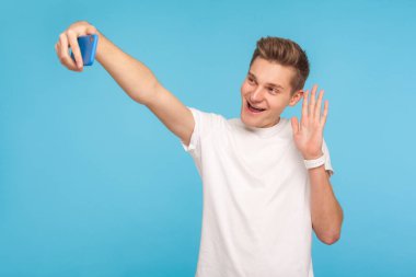 Friendly happy man in casual white t-shirt gesturing hello, sayi
