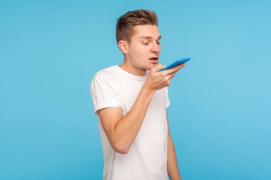 Smart voice technology. Young man in t-shirt saying command to s