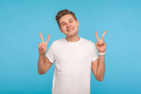 Retrato de feliz hombre encantado en camiseta blanca que muestra la victoria — Foto de Stock