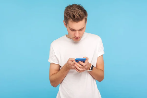 Portrait of young man in white t-shirt using cellphone with focu — Stok fotoğraf