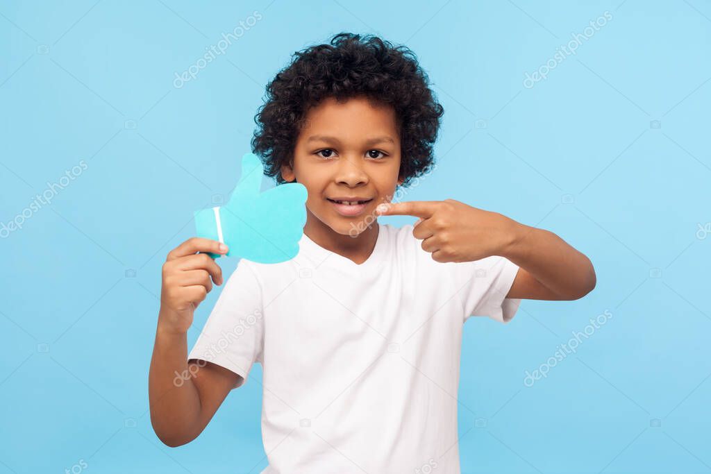 Portrait of happy nice preschool boy pointing to blue Like icon 