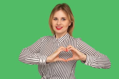 Charming kind girl with red lips in striped blouse making heart 