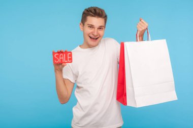 Excited happy man holding sale inscription and shopping bags, sm