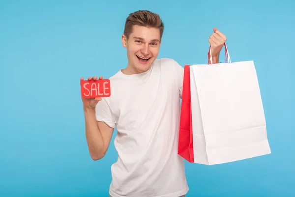 Excited happy man holding sale inscription and shopping bags, sm — Stok fotoğraf