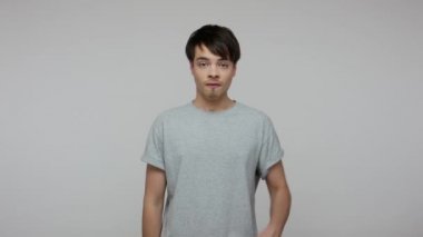 Crazy rude vulgar man in T-shirt showing middle fingers with both hands and saying fuck you, expressing protest aggression hate, impolite behavior. indoor studio shot isolated on gray background