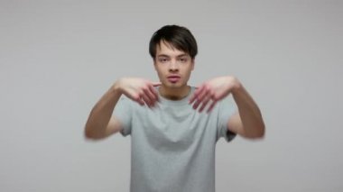Get out! Dissatisfied guy in T-shirt gesturing go away, asking to leave him alone, looking bored with talk showing direction out, breakup, end of relations. studio shot isolated on gray background