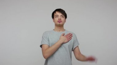 I swear! Responsible serious young guy giving promise with raised hand and nodding approvingly, honest trustworthy citizen making loyalty promise oath. indoor studio shot isolated on gray background