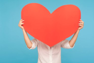 Sevgililer Günü 'nde isimsiz romantik bir randevu. Büyük bir kalbin arkasına saklanan, büyük bir aşk sembolü ile büyük romantik duygularını ifade eden bilinmeyen bir kadın. Mavi arka planda kapalı stüdyo çekimleri