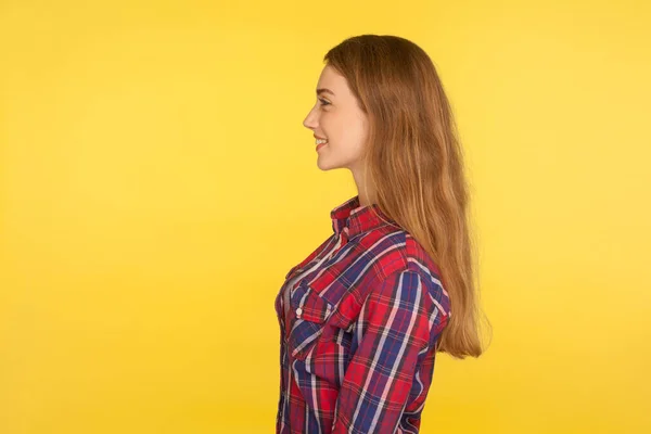 明るい幸せな表情 美しさとスキンケアとコピースペースを見て長い生姜の髪を持つ小切手シャツで幸せな魅力的な若い女の子のサイドビュー 黄色の背景に隔離されたスタジオショット — ストック写真