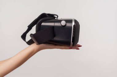 Kadın elinin VR gözlükleri, sanal gerçeklik gözlüğü siber uzay simülasyonu, yenilikçi teknolojiler, gelecek ve bilim için 3D kulaklık. Gri arka planda kapalı stüdyo çekimi