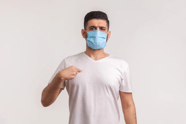 Man in surgical mask pointing himself, wearing protective filter to prevent coronavirus infection, airborne respiratory illness such as flu, 2019-nCoV, ebola. studio shot isolated on white background